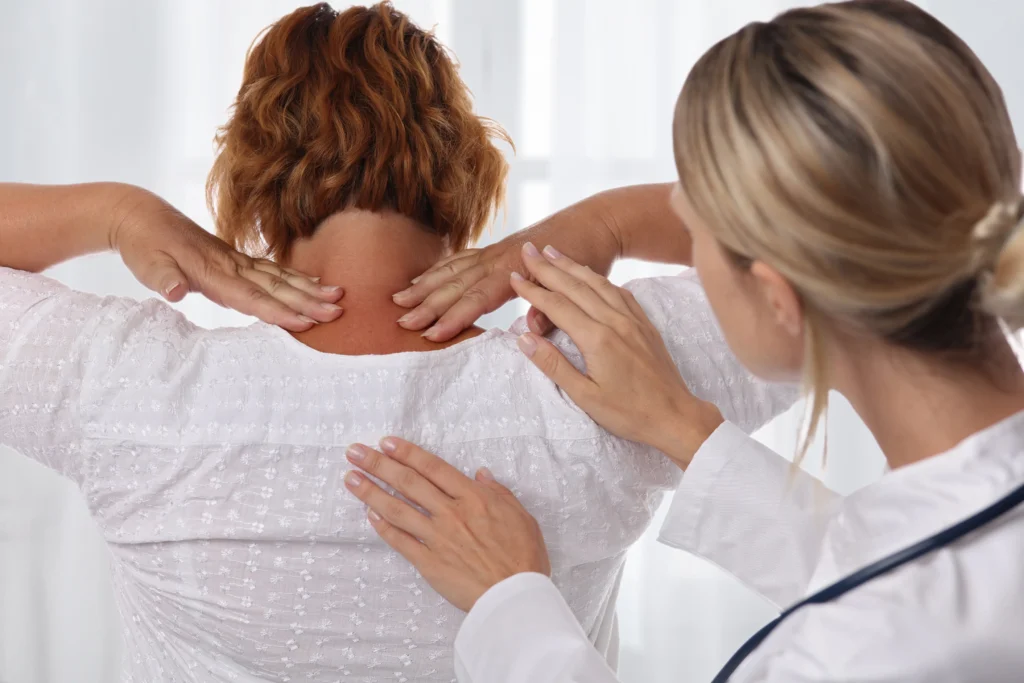 Woman suffering from back pain during medical exam. Chiropractic, osteopathy, Physiotherapy. Alternative medicine, pain relief concept.